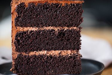 Slice of three-layer devil's food cake on a grey plate.