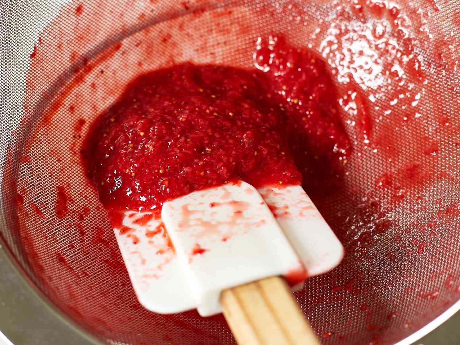 an upclose look at the seeds left in a strainer after making strawberry sauce