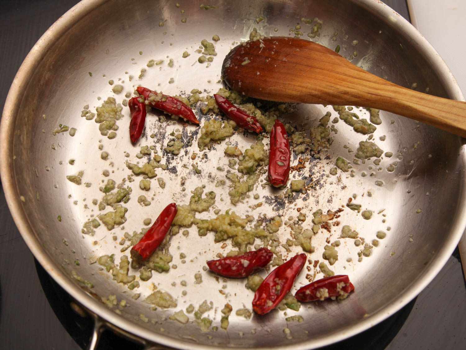 Sauteing garlic and chiles in a stainless steel skillet for General Tso's chicken.