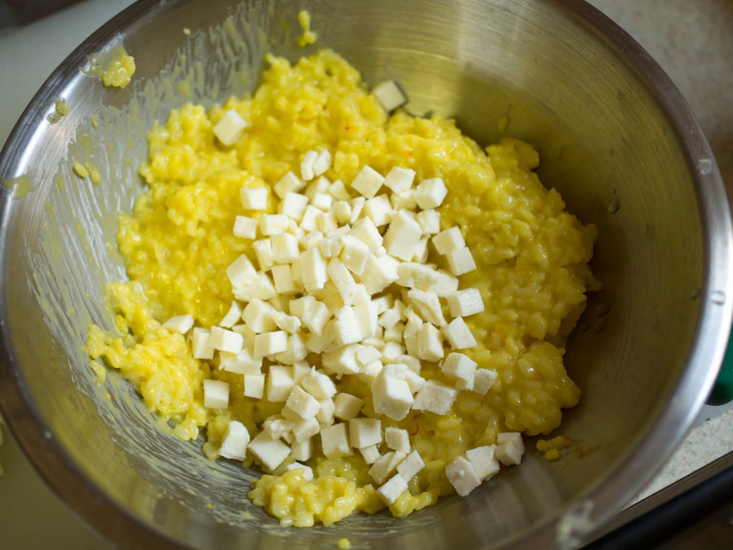 马苏里拉奶酪块堆在米饭和白酱汁的混合物上，放在搅拌碗里。