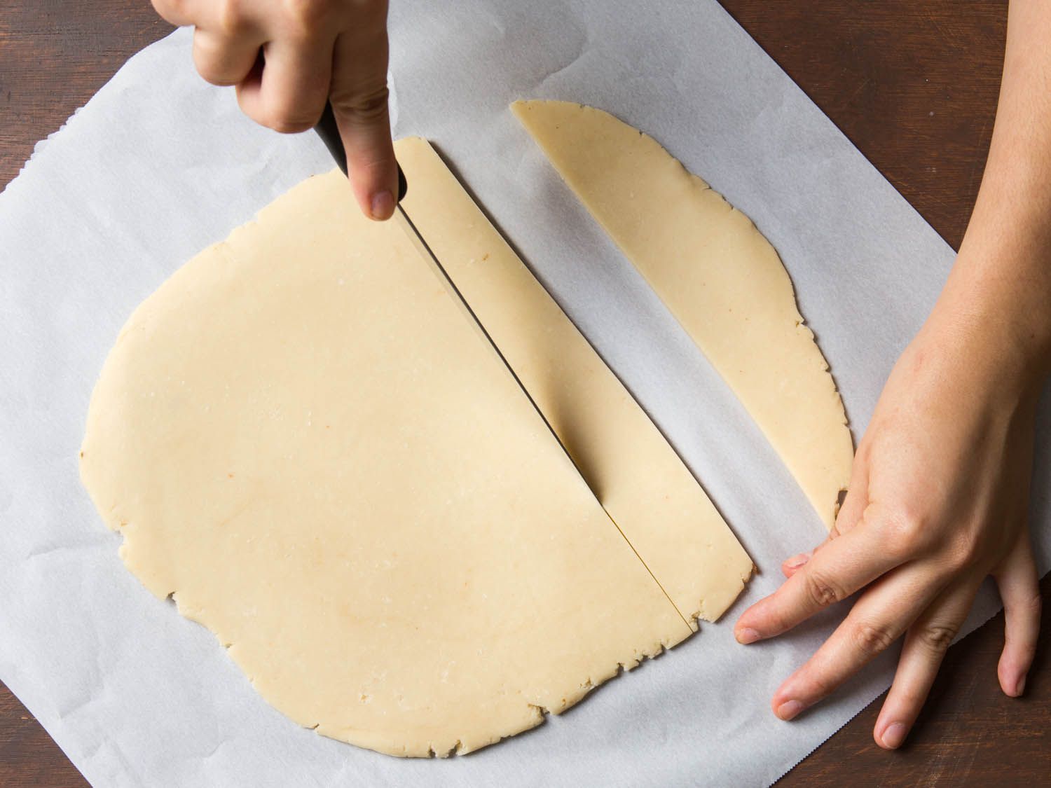 Cutting thin strips out of a flat slab of shortbread dough.