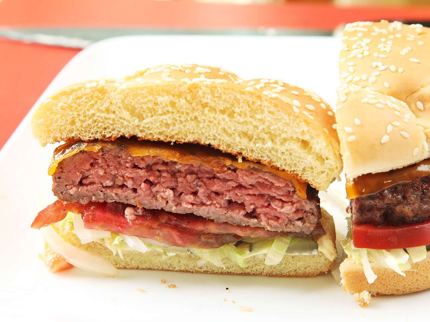 一张用真空烹调的芝士汉堡的横截面照片，配上生菜和西红柿放在芝麻面包上。gydF4y2Ba