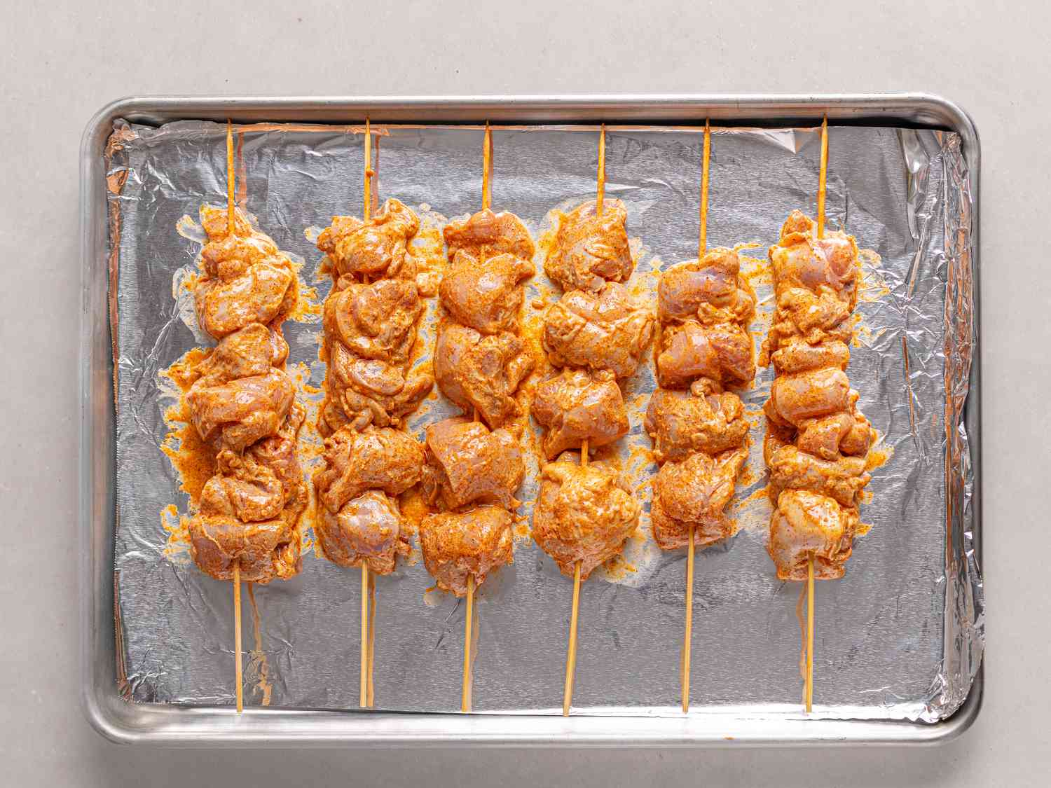 Overhead view of chicken threaded on skewers