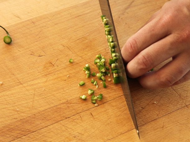 厨师用刀在砧板上把青椒条切成小块
