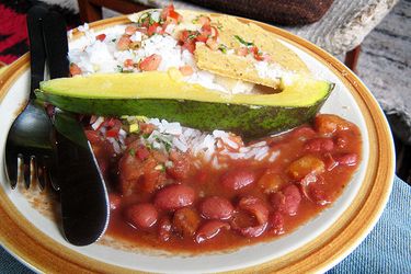 Colombian style beans and rice, bandeja paisa, with aji (Colombian style salsa) and an avocado wedge.