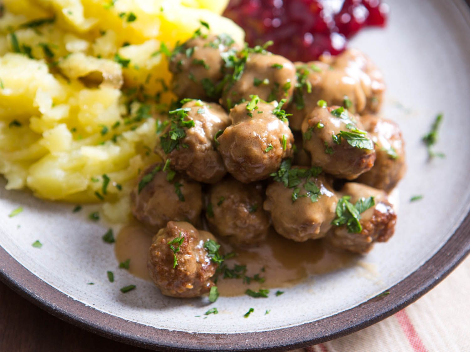 A plate with gravy-covered Swedish meatballs and mashed potatoes.