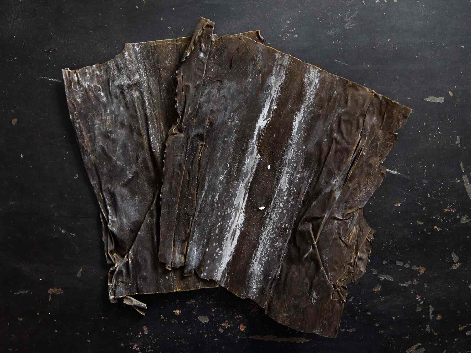 Dried kombu with a white dusting of crystalline glutamatic acid on its surface.