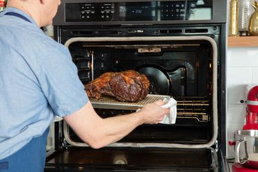 A prime rib roast is removed from an oven.