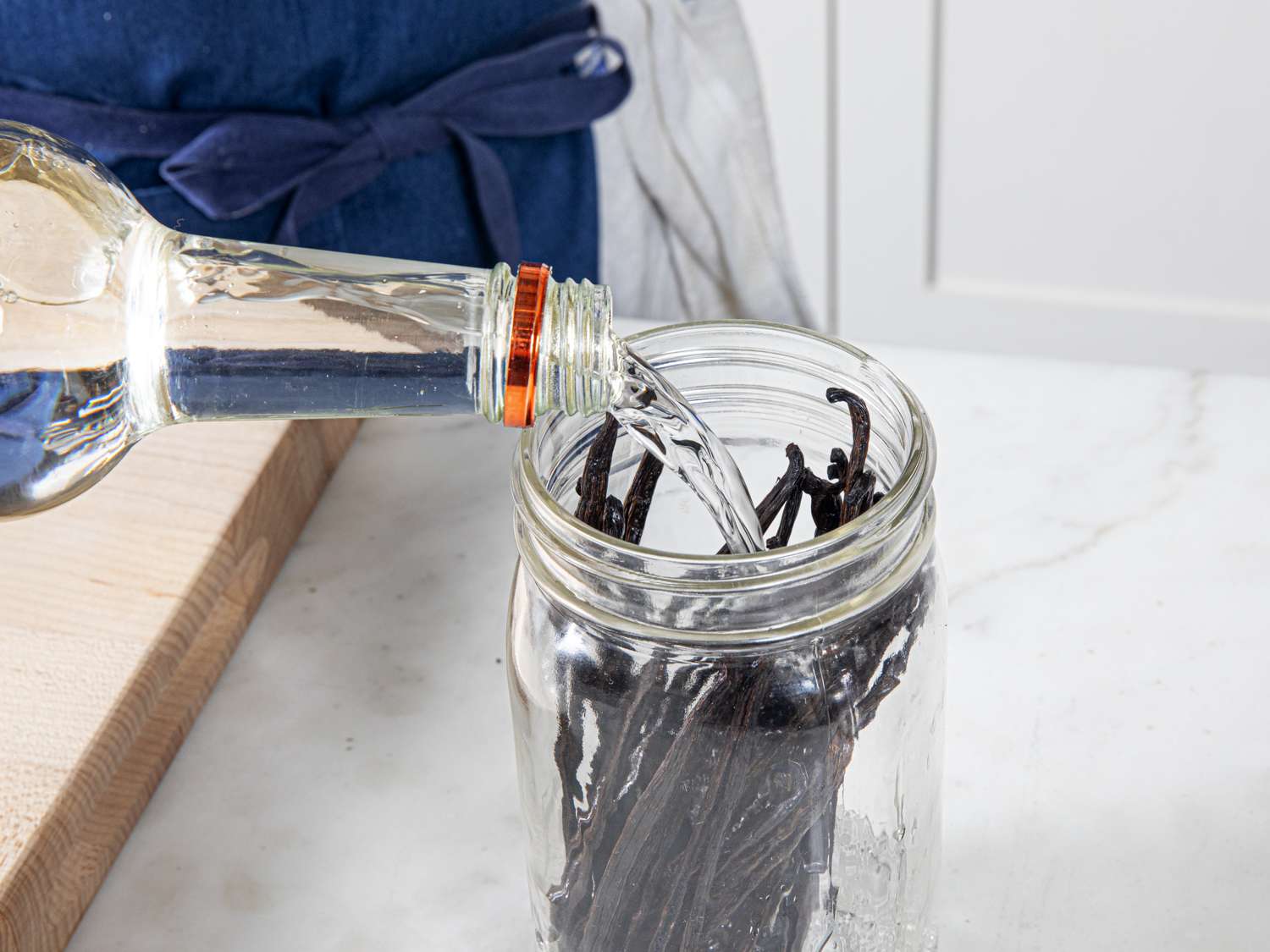 Pouring vodka into jar with vanilla beans