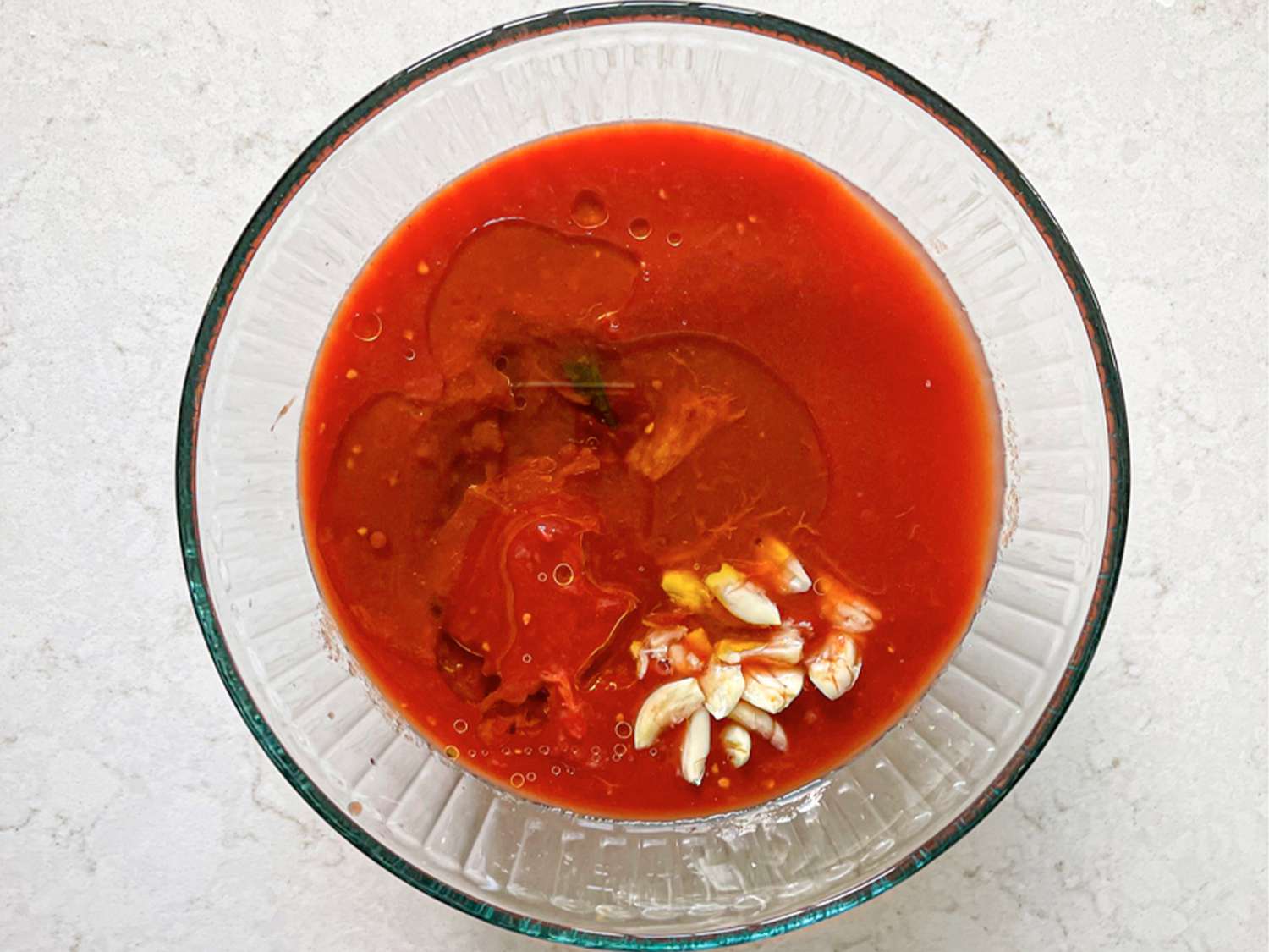 在玻璃碗里放上碎番茄，浇上橄榄油和大蒜