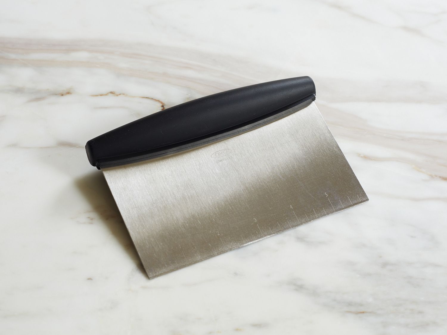 the oxo bench scraper on a marble countertop