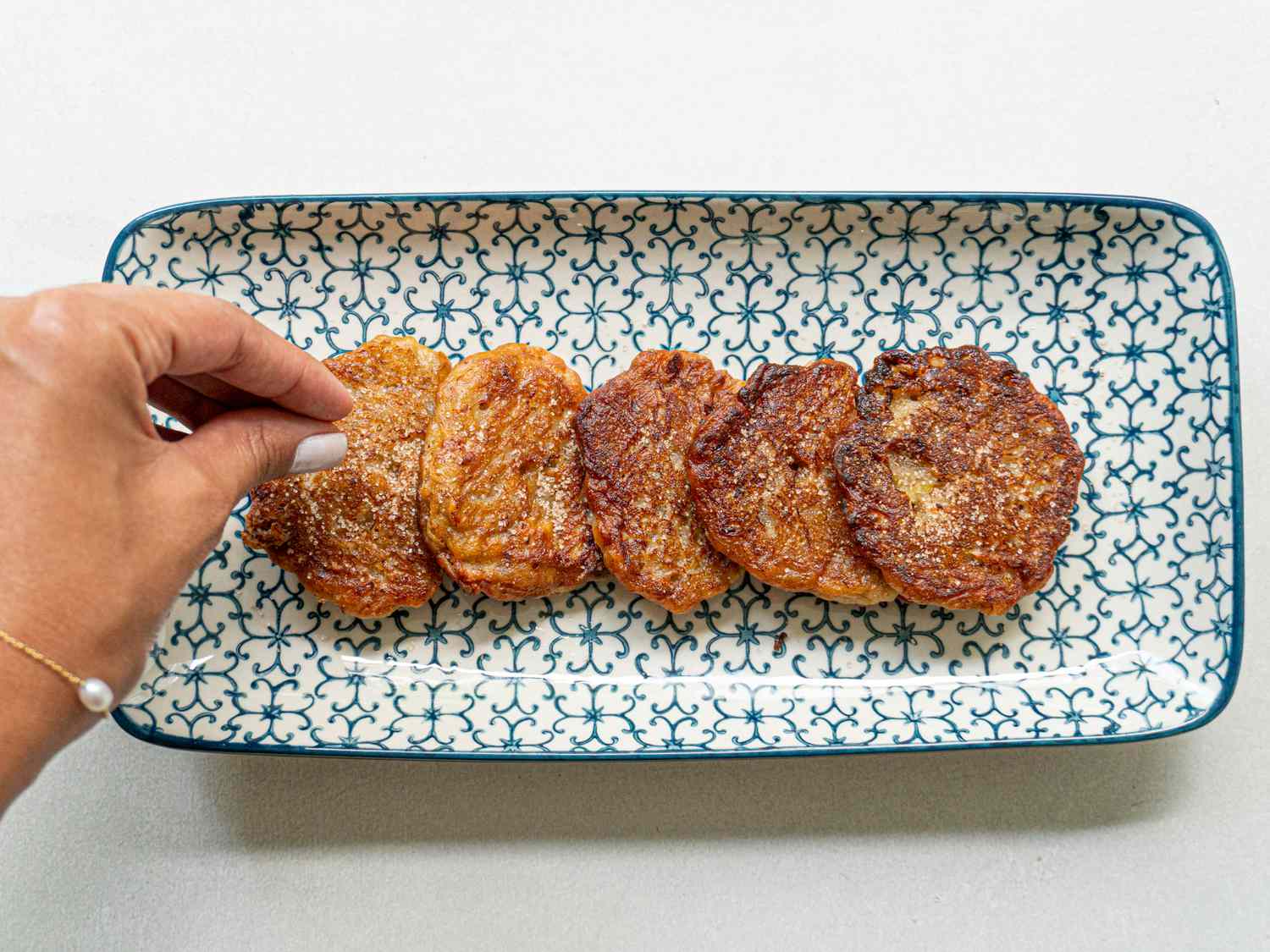 Overhead view of sprinkling sugar on banana fritters