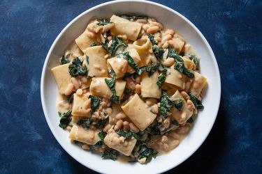 A bowl of rigatoni with greens and beans.