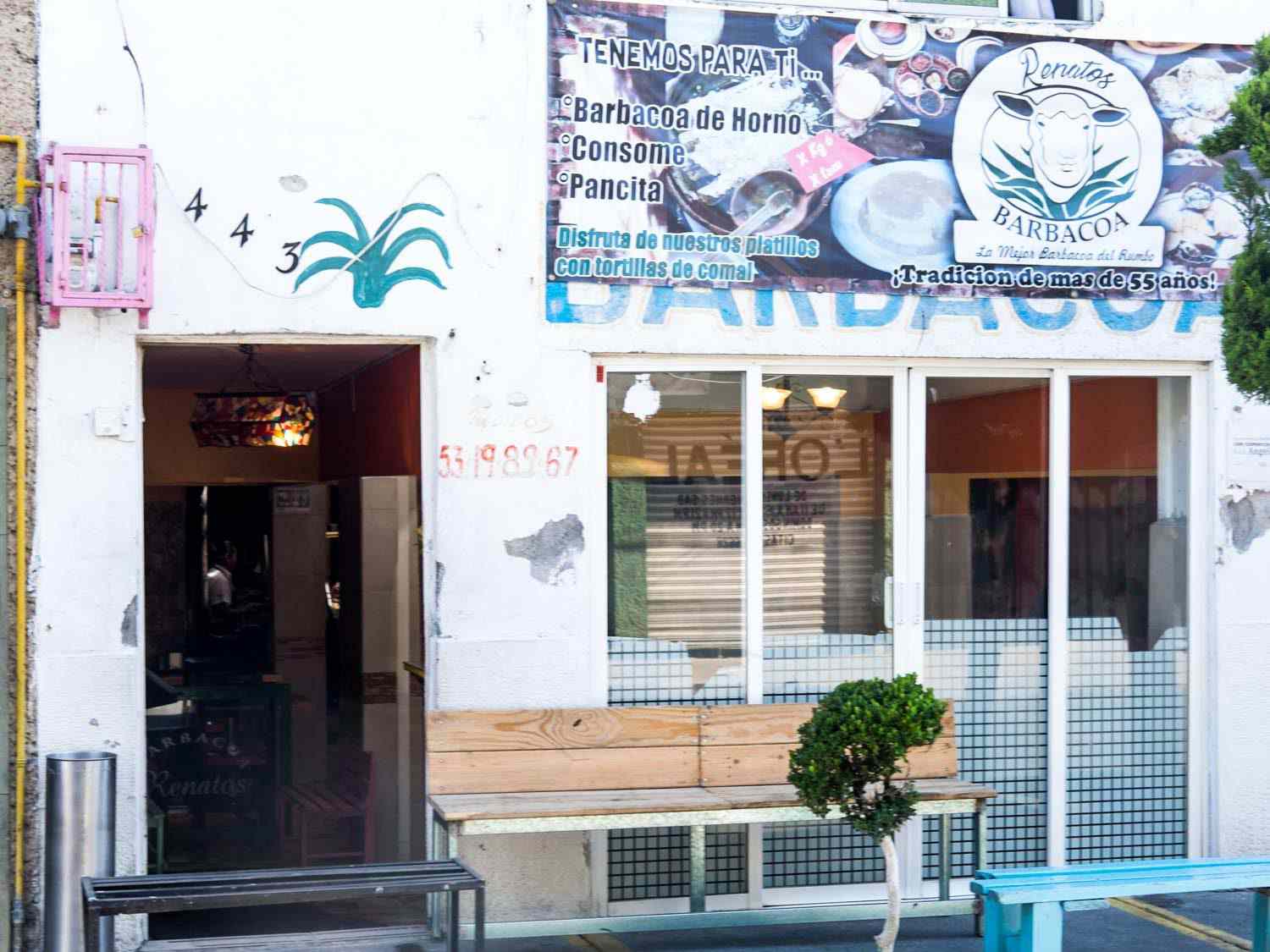 墨西哥城一家名为Barbacoa Renatos的烤肉餐厅的外观，门外有长凳，菜单上有横幅广告