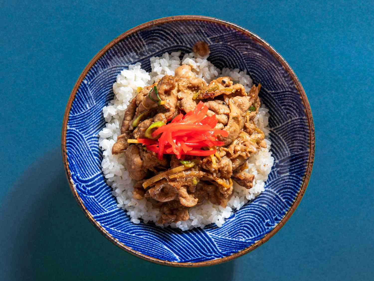 在蓝色图案的碗里盛上猪肉姜和米饭，并配以日本菜