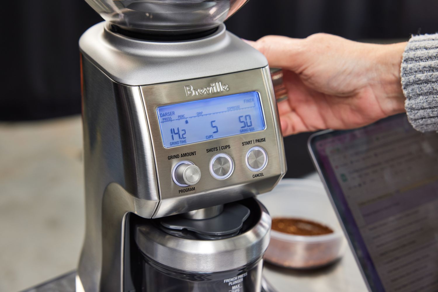 A person adjusting the grind setting of a breville coffee grinder