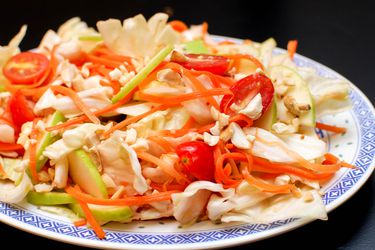 Spicy Cabbage Salad with sliced green apple, julienned carrots, and cherry tomatoes on a platter