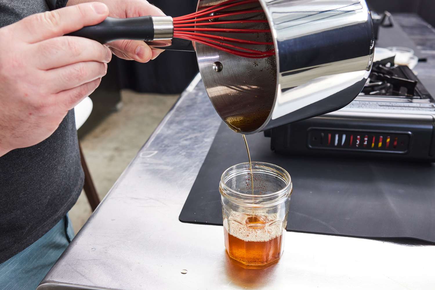 一个person pouring browned butter from a saucepan into a jar