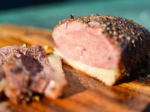 Closeup of a sliced duck breast pastrami on a wooden cutting board