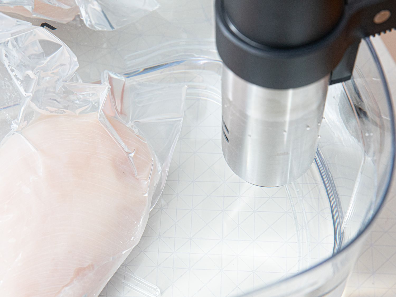 sous vide bath with chicken in plastic bag and sous vide to the right