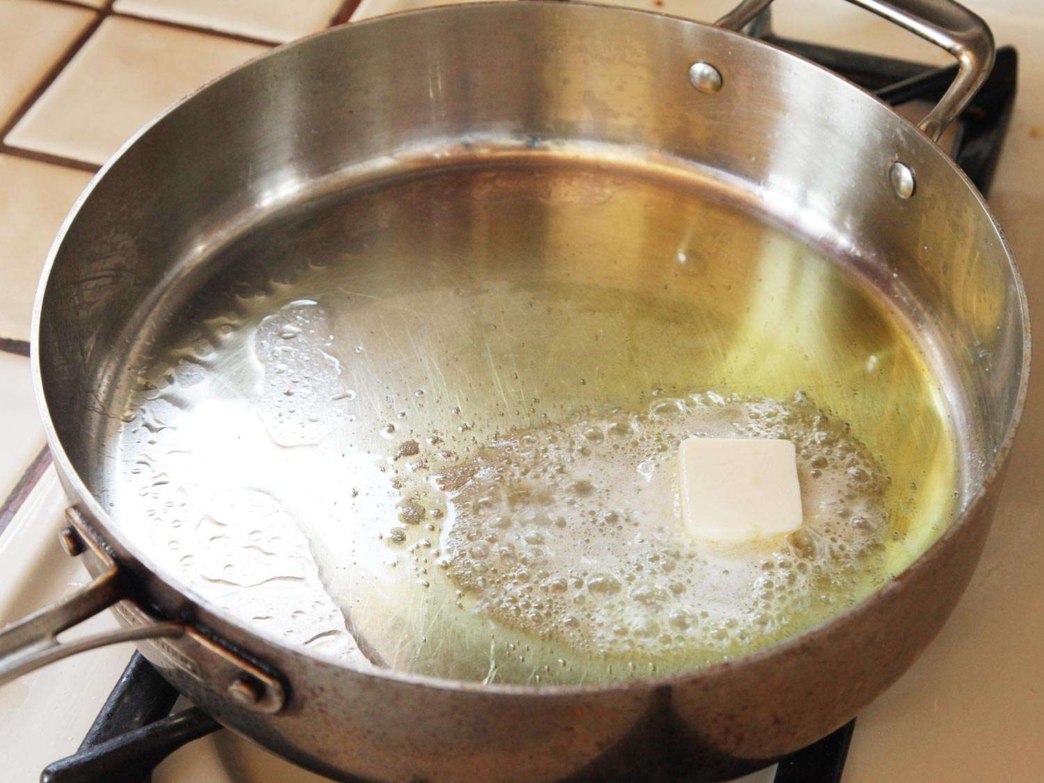 黄油在一个大的平底锅里和橄榄油一起起泡融化。