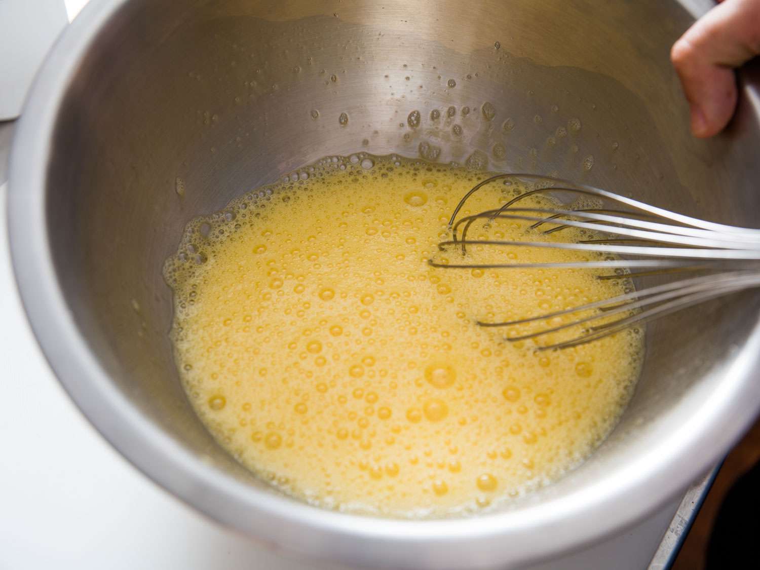 Beating eggs in a metal bowl with a whisk until frothy.