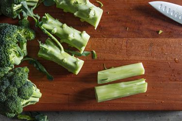 broccoli stems that have been cut off on a wood cutting board with a knife.