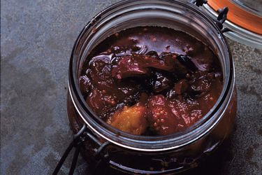 An open glass mason clamp jar filled with plum chutney.