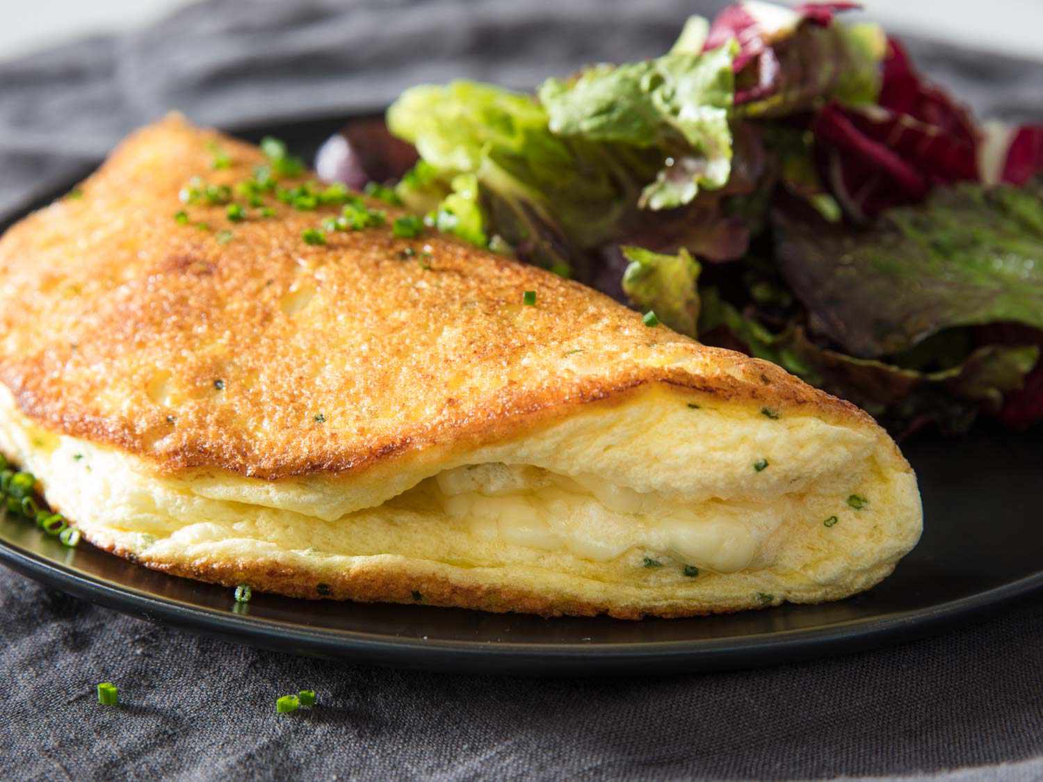 A fluffy soufflé cheese omelette plated with mixed greens