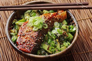 A teriyaki-glazed salmon rice bowl with chopsticks