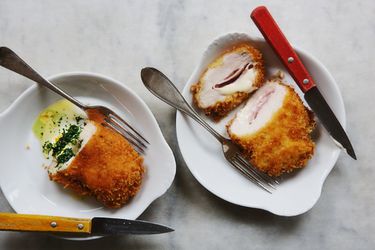 Two chicken cordon bleu in dishes, one with ham and cheese and one with an herb filling.