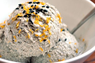 Three scoops of black sesame and orange ice cream in a bowl