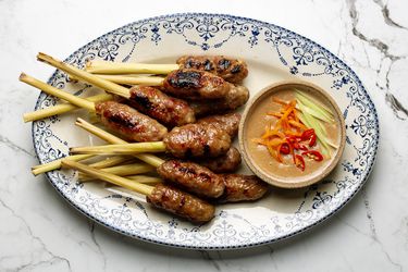 Platter with pile of nem lui skewers next to dipping sauce ramekin