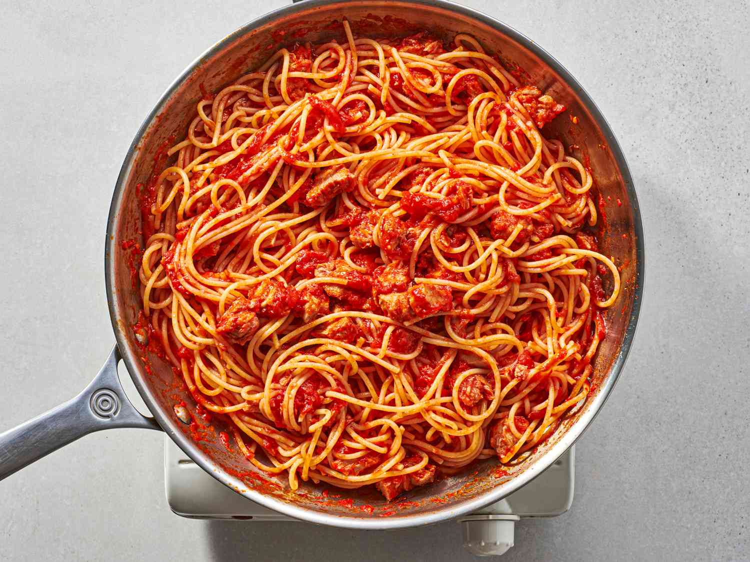 Pasta stirred and tossed with sauce in a large skillet