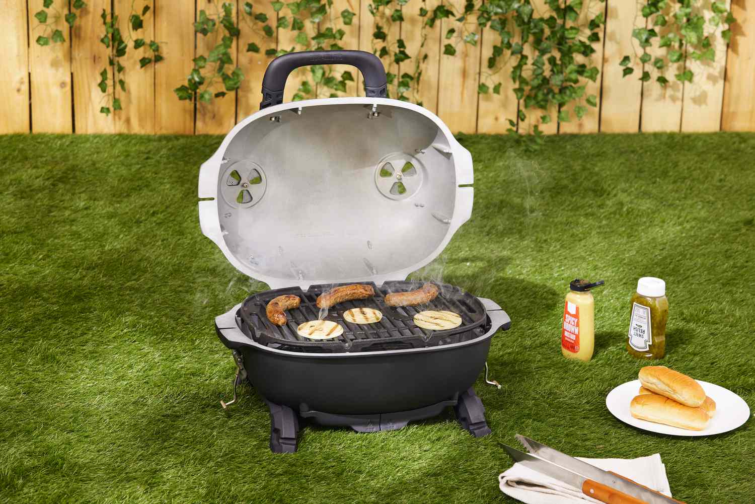 一个便携式木炭烤架在草坪上烤香肠