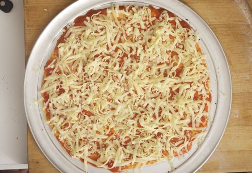 A bar-style pizza with shredded cheese on top, not cooked.