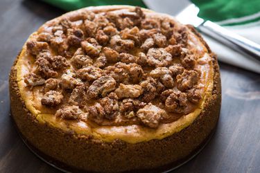 Pumpkin Cheesecake With Gingersnap Crust on a wooden surface with a cake server on the side.