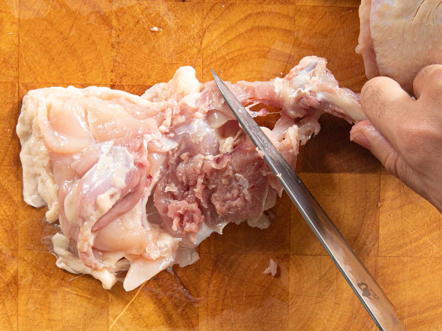 Overhead view of pulling the thigh bone away from the meat