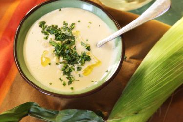 Creamy pressure cooker corn soup served in a bowl with soup, garnished with minced chives and tarragon, and extra-virgin olive oil