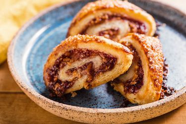 Three almond-raspberry rugelach on a ceramic plate.