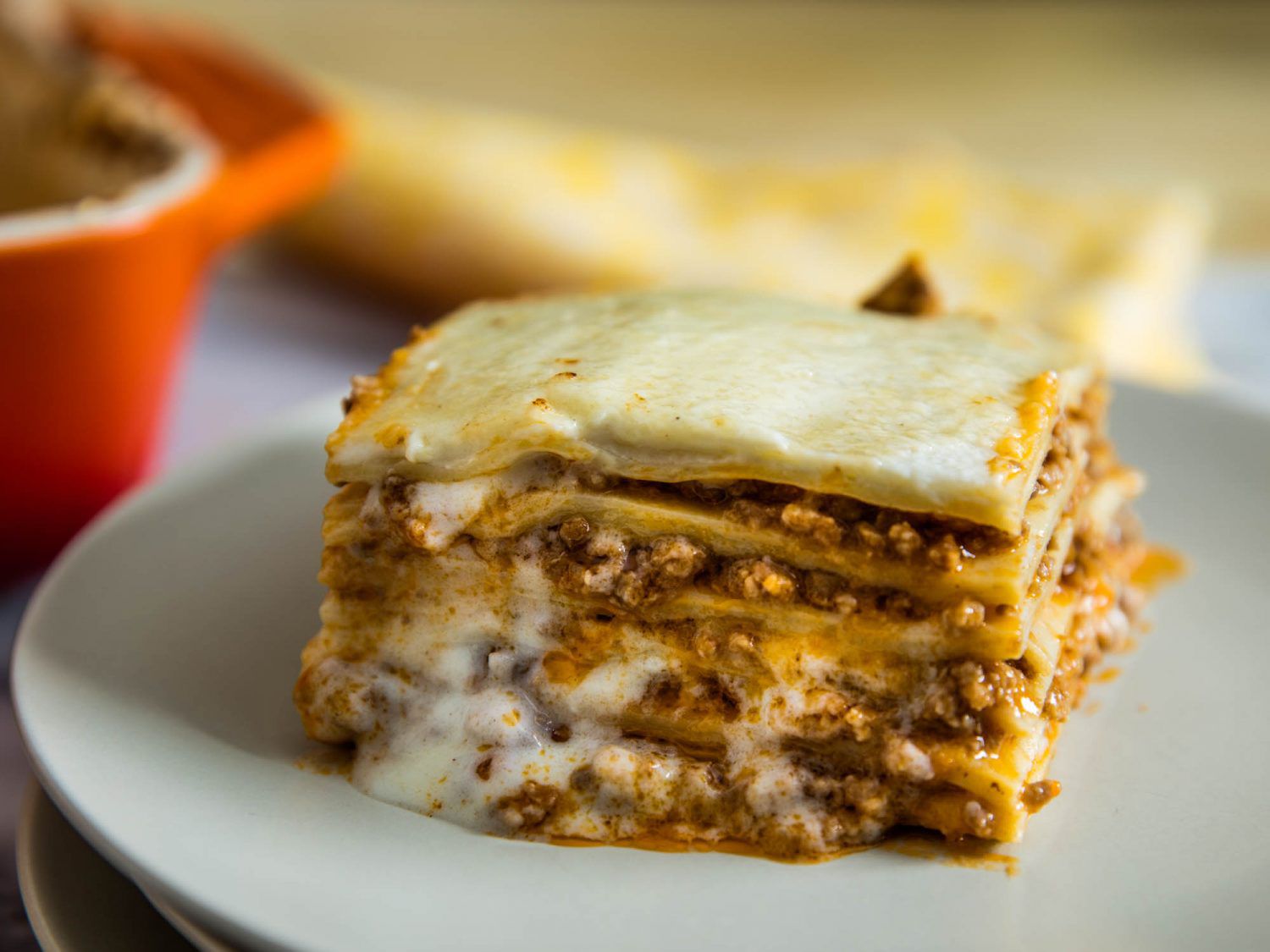 A healthy slice of lasagna Bolognese served on a white plate.