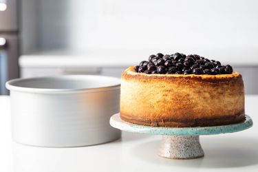 cheesecake on a cake stand beside a cheesecake pan