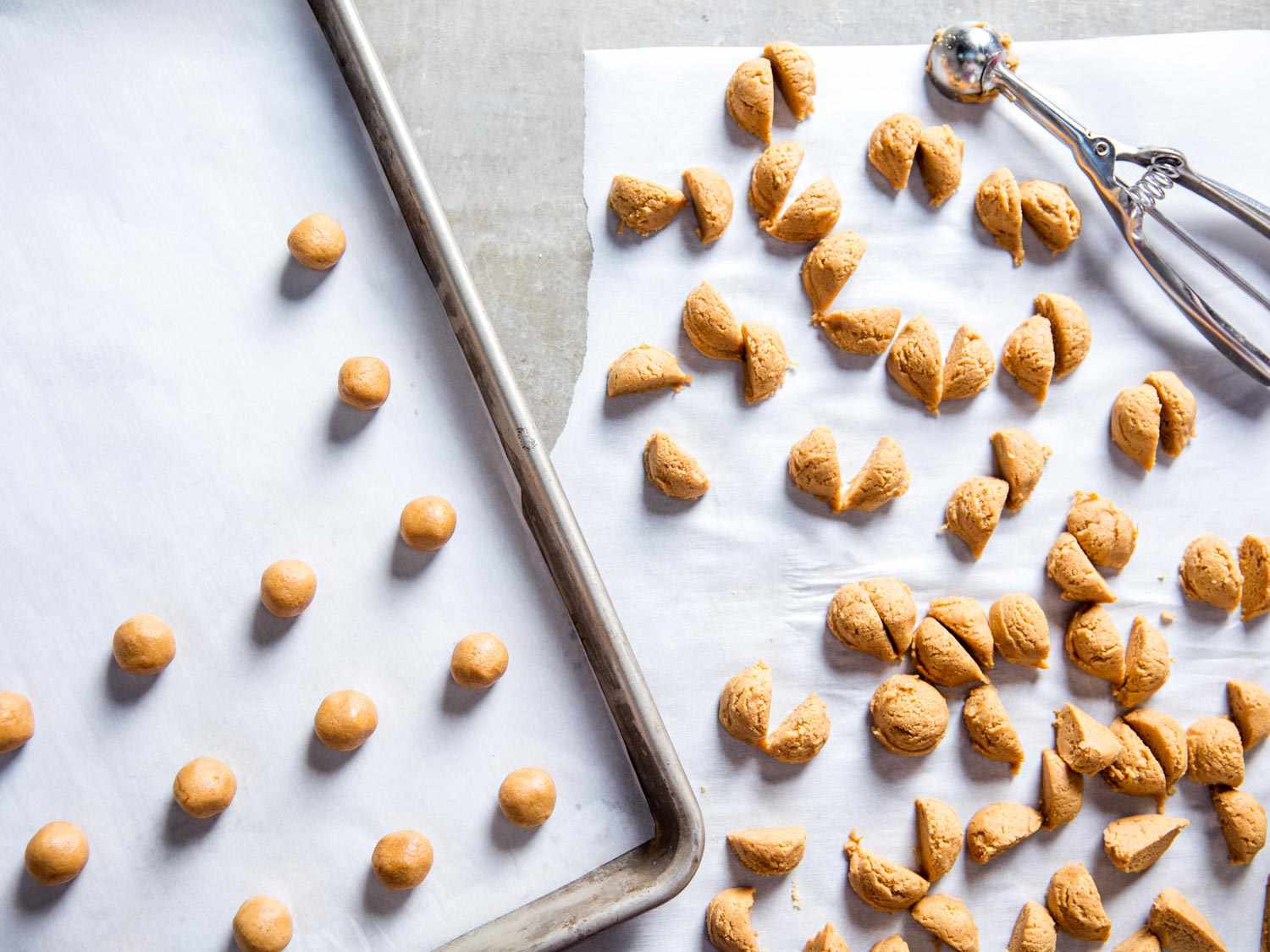 Scoops of the cookie dough are split in half, then rolled into balls and transferred to a parchment-lined baking sheet.