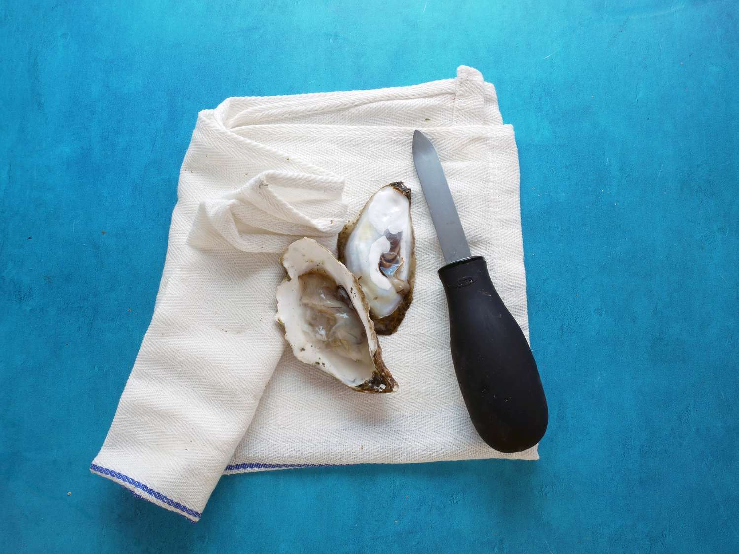 oxo oyster knife on a folded towel with shucked oyster