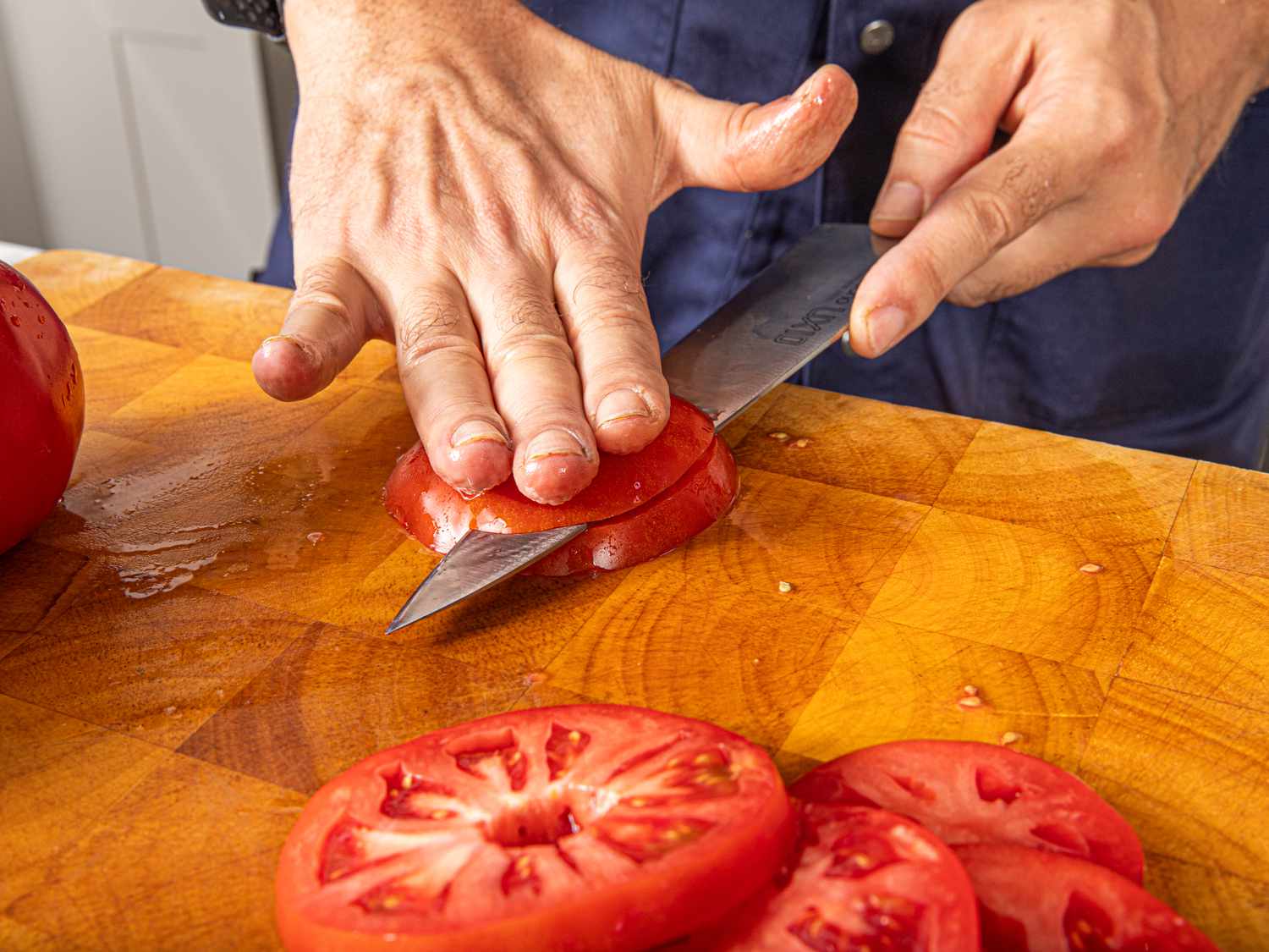 Overhead view of cutting bottom part of tomato off