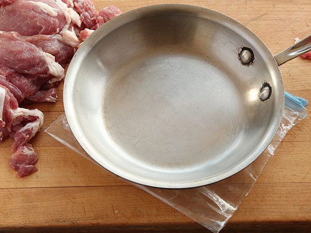 用一个厚煎锅将生猪肉片压平。切片放在塑料袋里，边切掉。