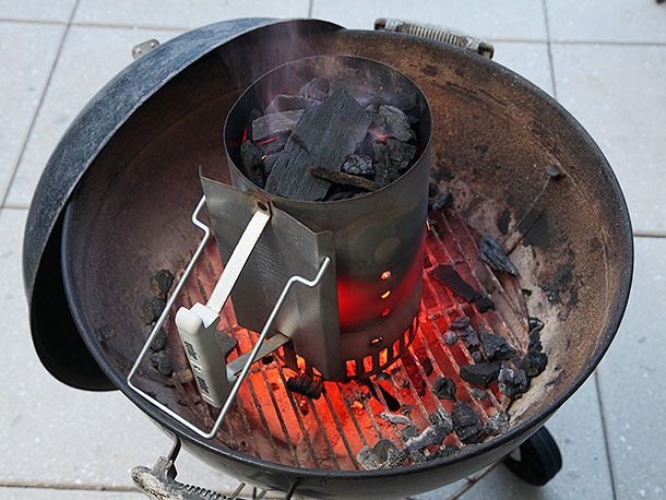 半燃的烟囱启动器，填充块状木炭，放置在水壶式烤架的底部格栅上。