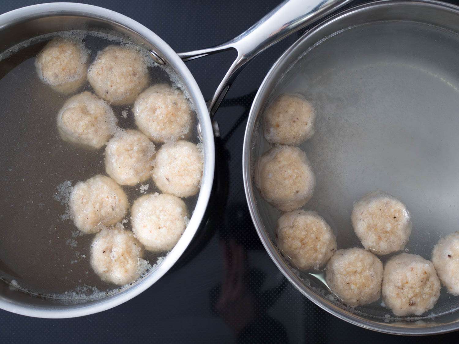 Two sauté pans of poaching matzo balls. The one on the right is filled with water, the one on the left broth.