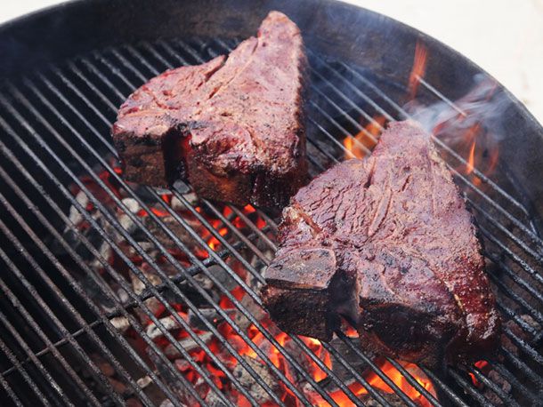 熏过的上等腰牛排被直接放回烤架上，放在滚烫的煤块上。