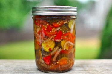 A pint-sized canning jar full of bread and butter pickles.